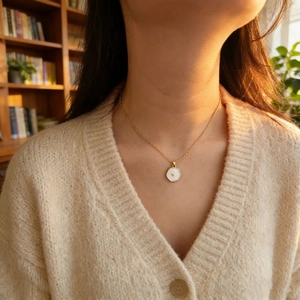 Dettaglio della collana dorata con pendente a cuore ottagonale bianco indossata
