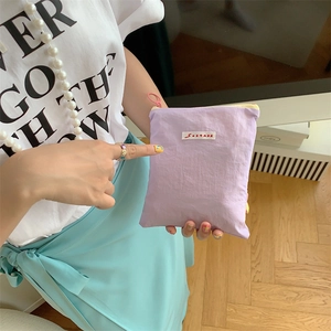 Macro shot of compact purple nylon pouch with zipper and woven brand label