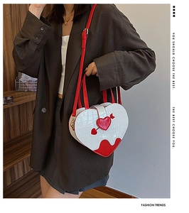 Close-up of white crocodile pattern heart-shaped crossbody bag with red arrow detail