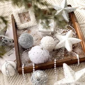 White and silver Christmas ball ornaments set with glitter stars on a knit blanket