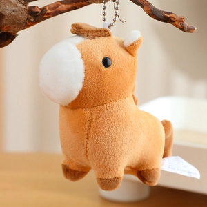 Detail of cute plush pony keychain hanging on a branch with soft brown fur texture