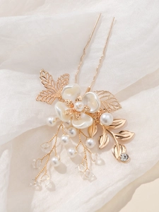 Detailed macro view of bridal hair pin featuring golden leaves and pearl tassel details