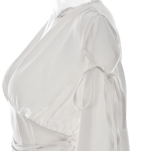 Détail de la blouse blanche en satin à manches longues avec col en V et poignets à lacets