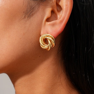 Macro shot of gold twisted knot earrings showing metallic luster and modern design on ear