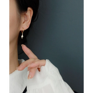 Macro view of gold-plated lightning bolt earrings with pavé stones on a model