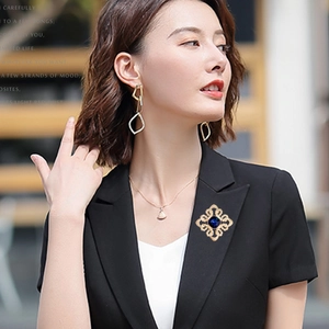 Macro detail of a vintage gold brooch with a deep blue crystal on a black blazer jacket