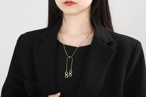 Detail of a gold titanium snake chain necklace with infinity pendants on a model