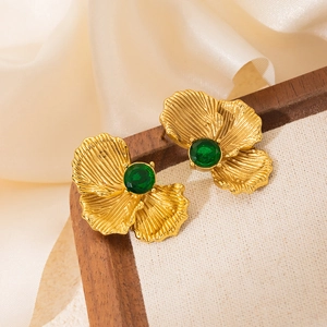 Detailed macro view of vintage gold petal earrings with a large green zircon gemstone