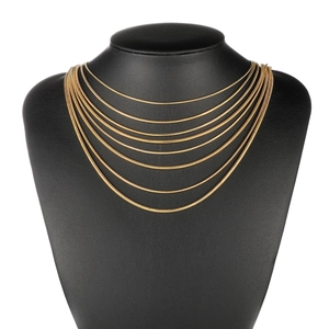 Multi-layered gold snake bone chain necklaces displayed on a black neck mannequin stand