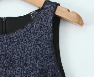 Detailed view of dark blue sequins and brand neck label on backless dress shoulder