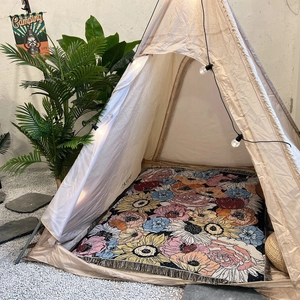 Detail shot of bohemian camping blanket with floral patterns and fringe in a cozy tent