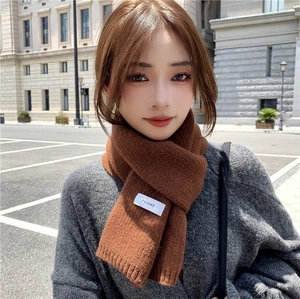 Detailed view of brown rib-knit scarf texture featuring a small white brand label