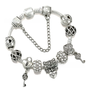Detailed macro of silver-plated charm bracelet with heart locket and safety chain