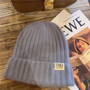 Detailed knit texture of blue and purple beanie with California 1982 patch on wood surface