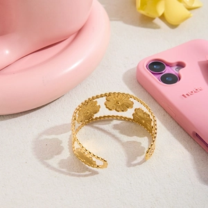 Detailed close-up of hollowed-out gold flower patterns on a stainless steel open cuff bracelet