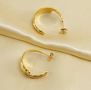 Detailed view of 18k gold plated stainless steel textured hoop earrings on golden silk fabric