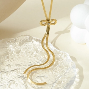 Detail of gold bow pendant necklace with rhinestone and elegant snake chain tassel