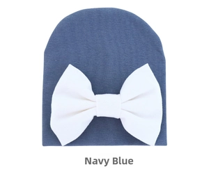 Detailed texture of navy blue baby knit hat featuring a large decorative white bow