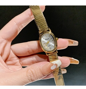 Detailed view of women's golden oval quartz watch with an elastic metal chain strap