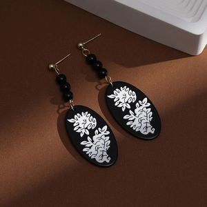 Close-up of Chinese style fan-shaped pearl tassel earrings with black floral patterns