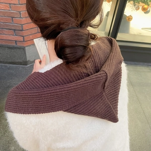 Rear view of a brown knitted hooded scarf shawl on a model in a street setting