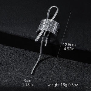 Silver bow metal hair clip with tassel chain on a black leather background