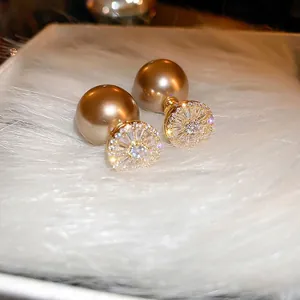 Elegant gold-plated double-sided pearl earrings with zircon crystals on plush background