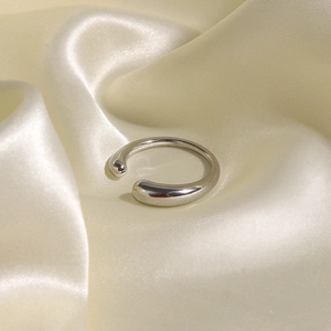 Detailed view of polished silver steel ring placed on soft beige silk fabric