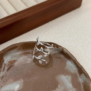 Macro shot of silver leaf branch ring on a vintage ceramic plate with rustic background