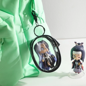 Clear PVC display pouch with black trim and clip attached to a light green backpack