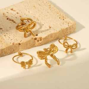 Golden butterfly open rings and jewelry displayed on minimalist textured stone background