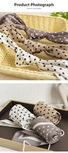 Detailed view of polka dot silk scarves in beige and pink with a satin finish