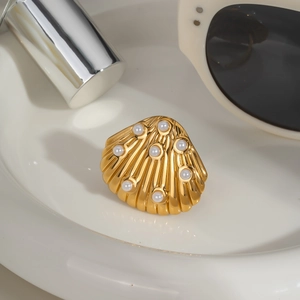 Detail shot of a golden shell-shaped earring with pearls on a white tray