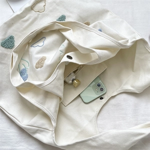 Detail of canvas tote bag interior with zipper pocket and embroidered cloud pattern
