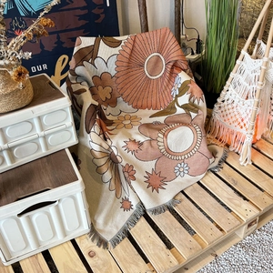Detail of vintage bohemian woven blanket with orange floral patterns and tassel edges