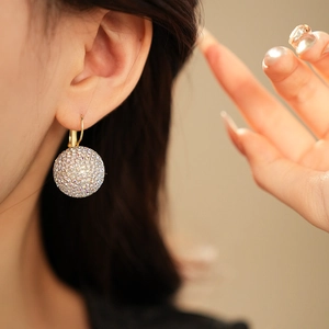 Close-up of elegant gold spherical drop earrings featuring shimmering pavé rhinestones