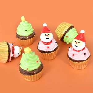 Miniature resin Santa and Christmas tree cupcake figurines on orange background
