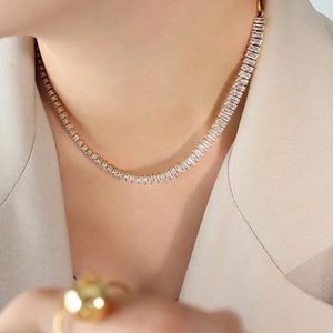 Golden tennis necklace with rectangular white zircons worn on female model neck