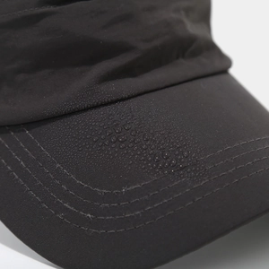 Macro shot of water droplets on black quick-dry baseball cap with waterproof fabric detail