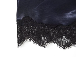 Détail de l'ourlet en satin bleu marine avec dentelle noire sur une robe courte