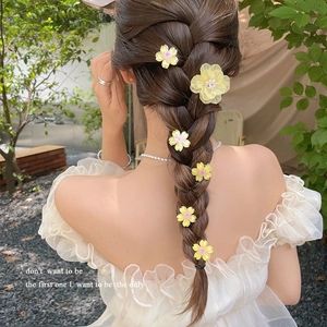 Pink and yellow cherry blossom hair clips set styled on a woman's braided hair