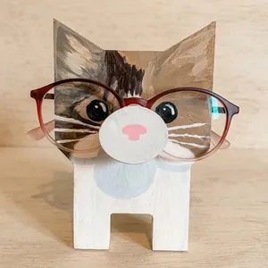 Detail showing a cat-shaped wooden glasses holder with red spectacles on a base