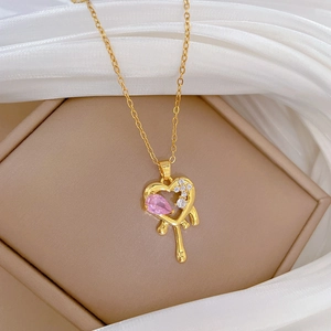Detail of gold melting heart necklace with pink gemstone on beige jewelry box