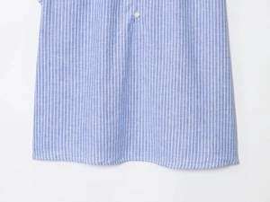 Gros plan sur les rayures bleues et blanches de l'ourlet d'une chemise en coton