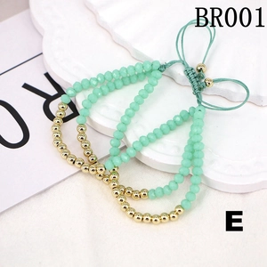 Detail of mint green and gold beaded woven bracelets set with adjustable cord on white plate
