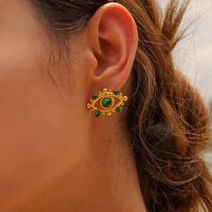Detail of gold evil eye stud earring with green malachite stone on model's ear
