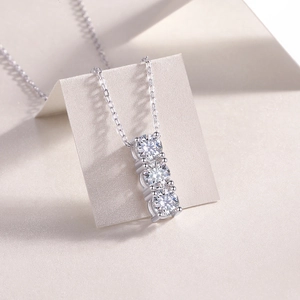 Macro shot of silver necklace featuring three vertical round-cut moissanite stones