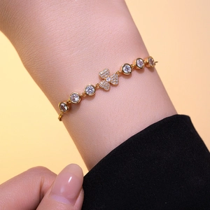 Bracelet raffiné plaqué or avec pendentif trèfle en zircon sur un poignet féminin