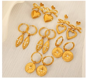Detailed set of gold titanium earrings featuring heart, bow, and sparkling leaf designs