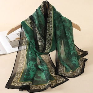 Detail of green floral and leopard print chiffon scarf draped on a wooden hanger